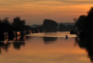 Canoeist at sunset, Gloucester and Sharpness Canal from Patch Bridge, Slimbridge, Gloucestershire, England, UK.